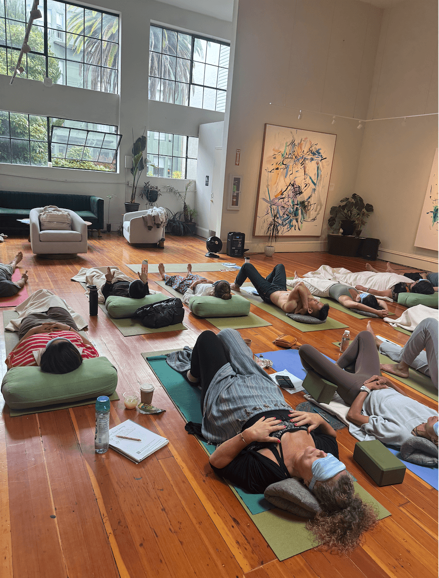 Participants resting on mats in a sunlit studio